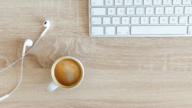 beverage filled mug near apple airpods with lightning connector and apple magic keyboard