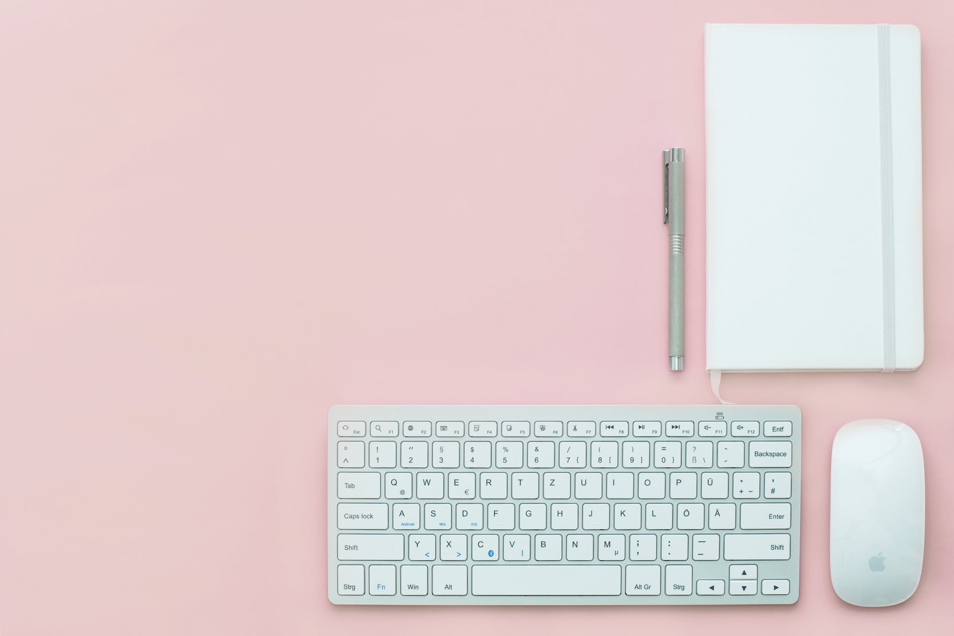 silver apple keyboard and magic mouse on a pink surface